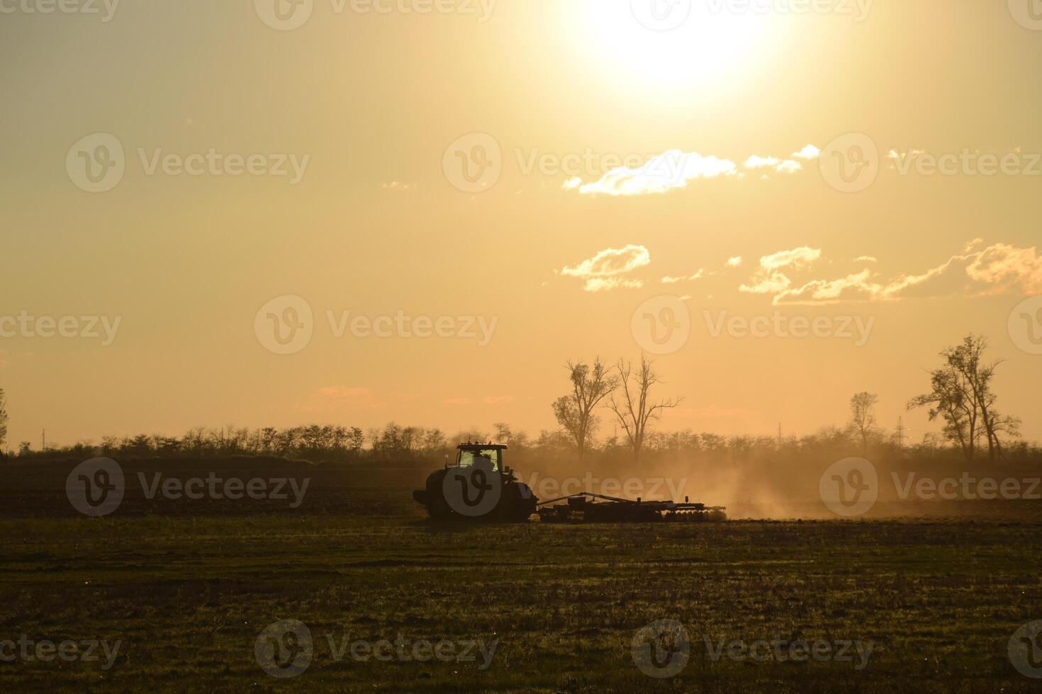 Tractor at sunset plow plow a field. Tilling the soil in the fall after harvest. The end of the season photo