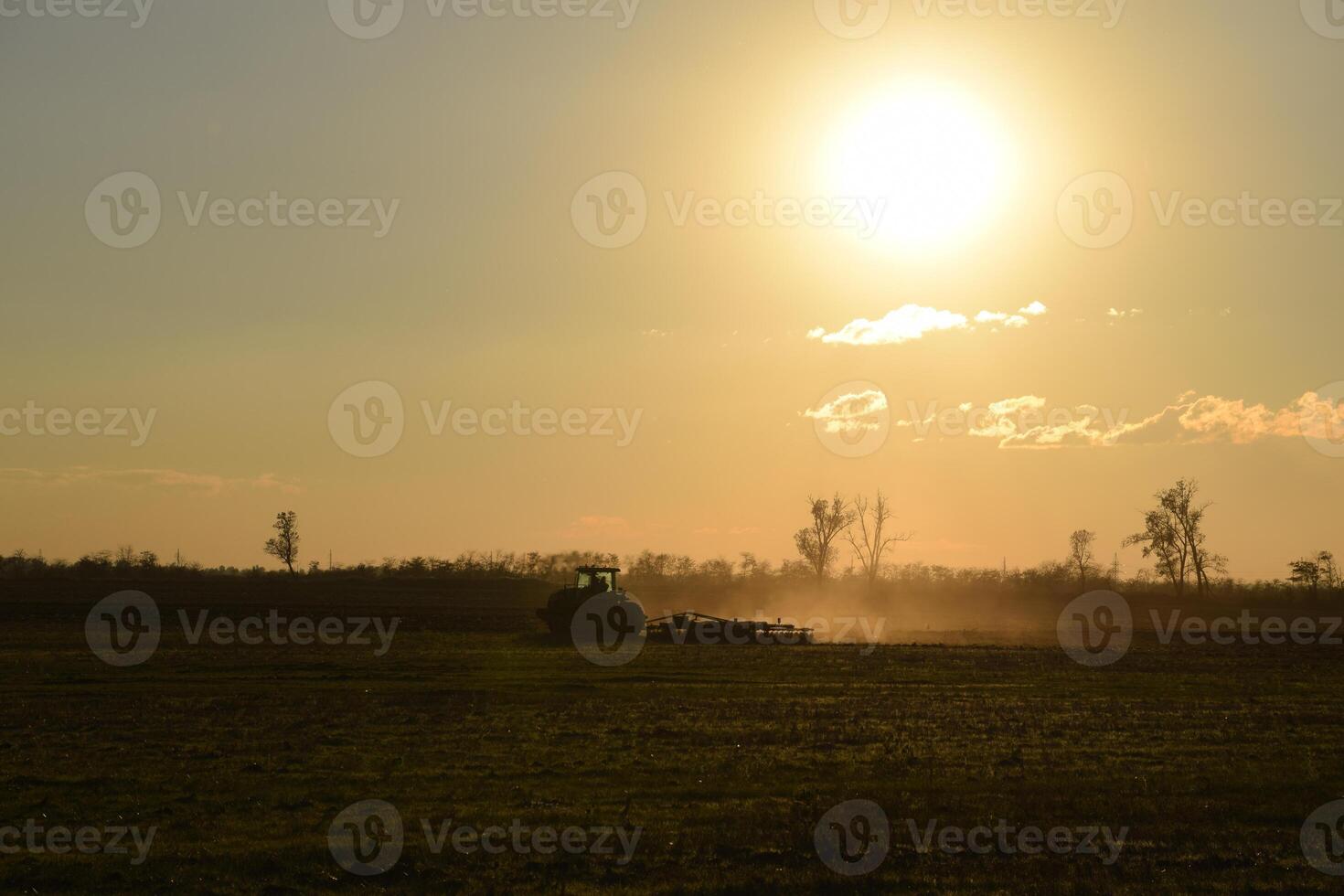 Tractor at sunset plow plow a field. Tilling the soil in the fall after harvest. The end of the season photo