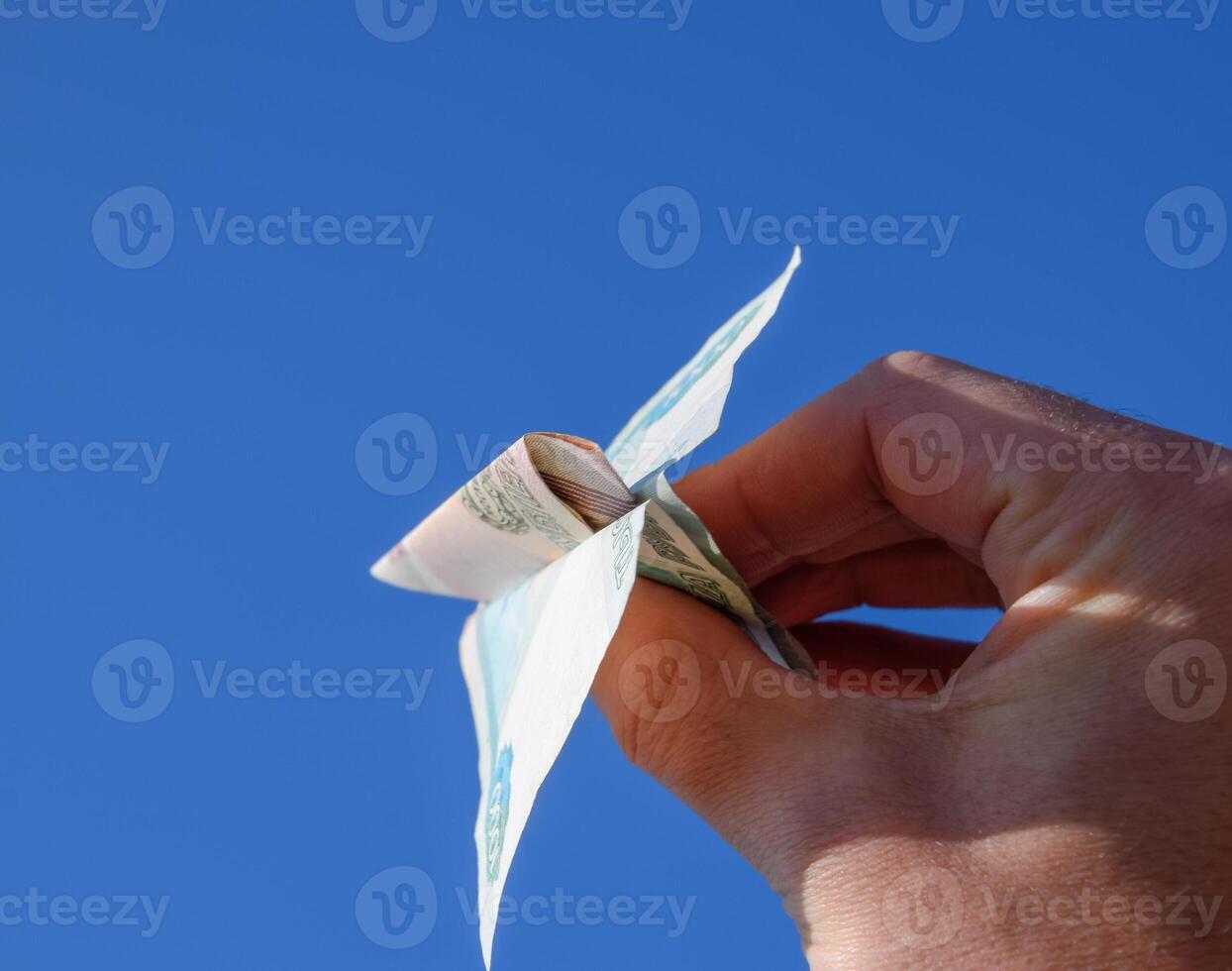 Denominations of Russian money, folded in the airplane against the blue sky in hand photo