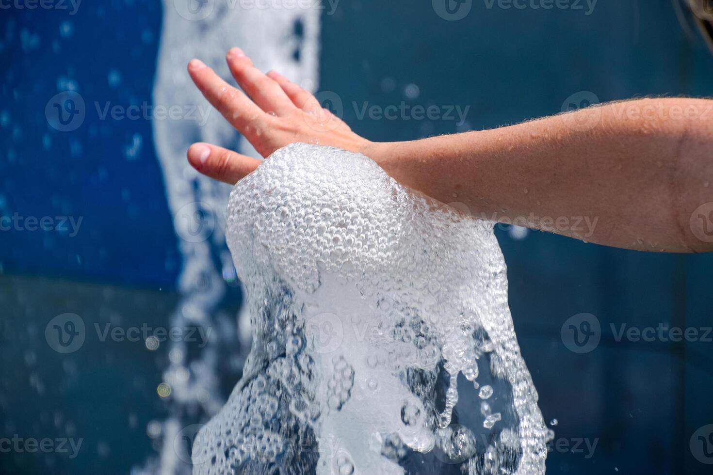 Hand touch the fountain. A stream of water from the fountain is touched by hand photo