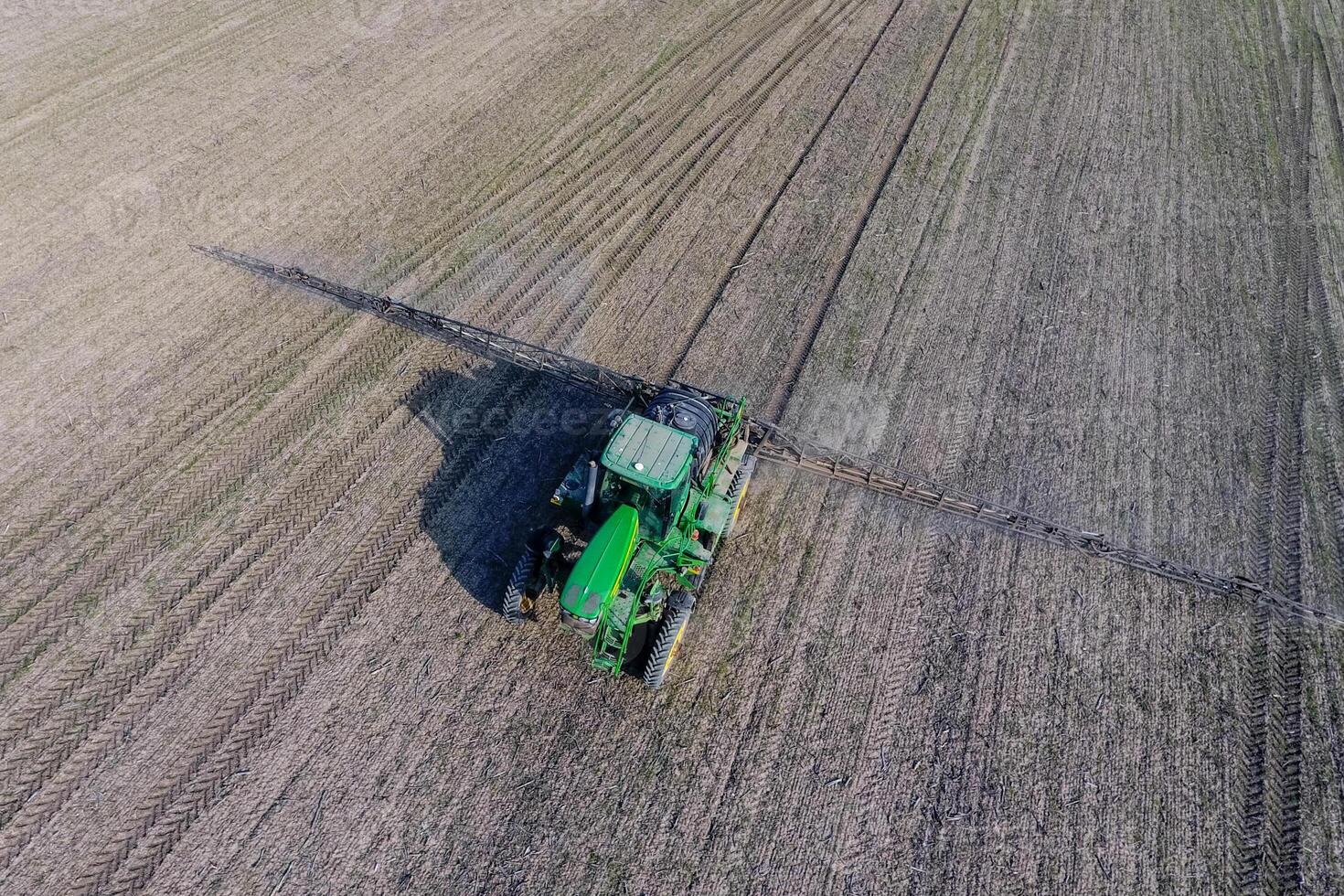 Tractor with hinged system of spraying pesticides. Fertilizing with a tractor, in the form of an aerosol, on the field of winter wheat. photo