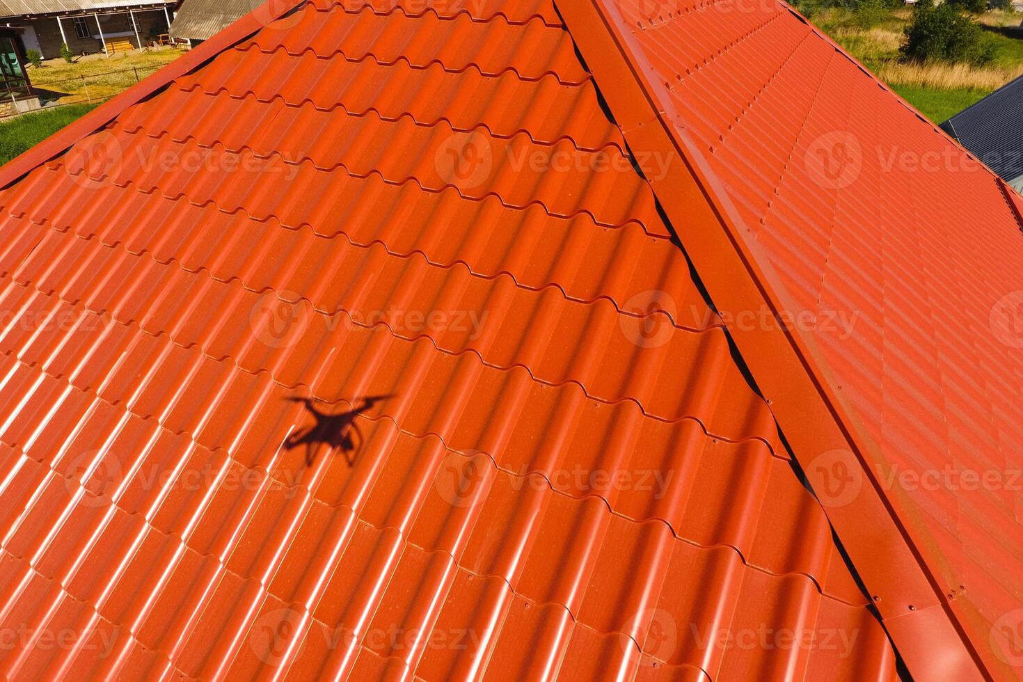 House with an orange roof made of metal, top view. Metallic profile painted corrugated on the roof. photo