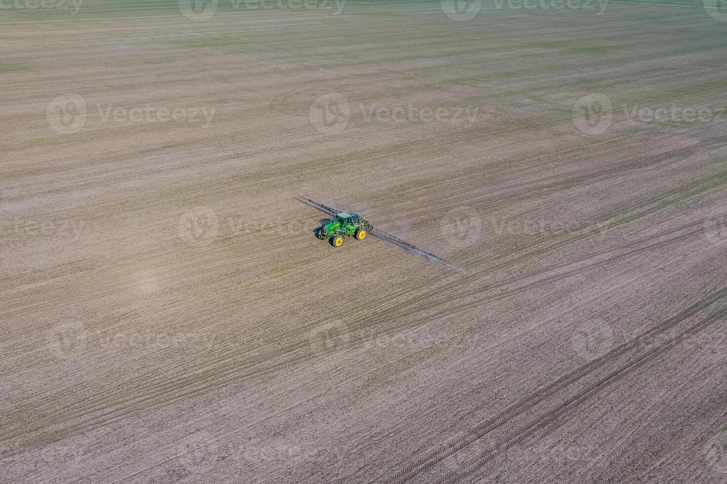 Tractor with hinged system of spraying pesticides. Fertilizing with a tractor, in the form of an aerosol, on the field of winter wheat. photo