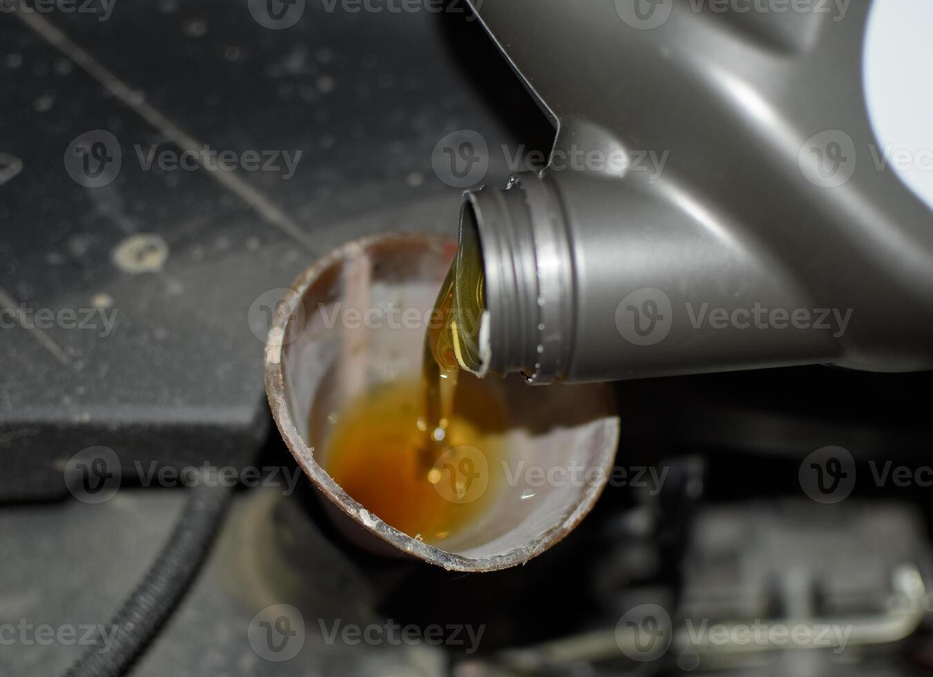 Oil change in the engine of the car. Filling the oil through the funnel. Car maintenance station. photo