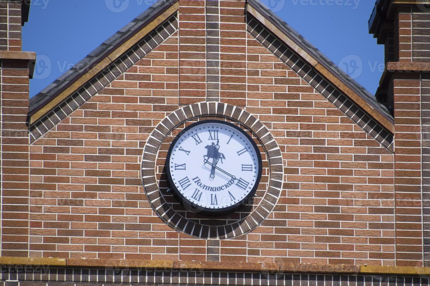 Clock on the wall of a brick building. Brown brick building with boshni and hours. photo