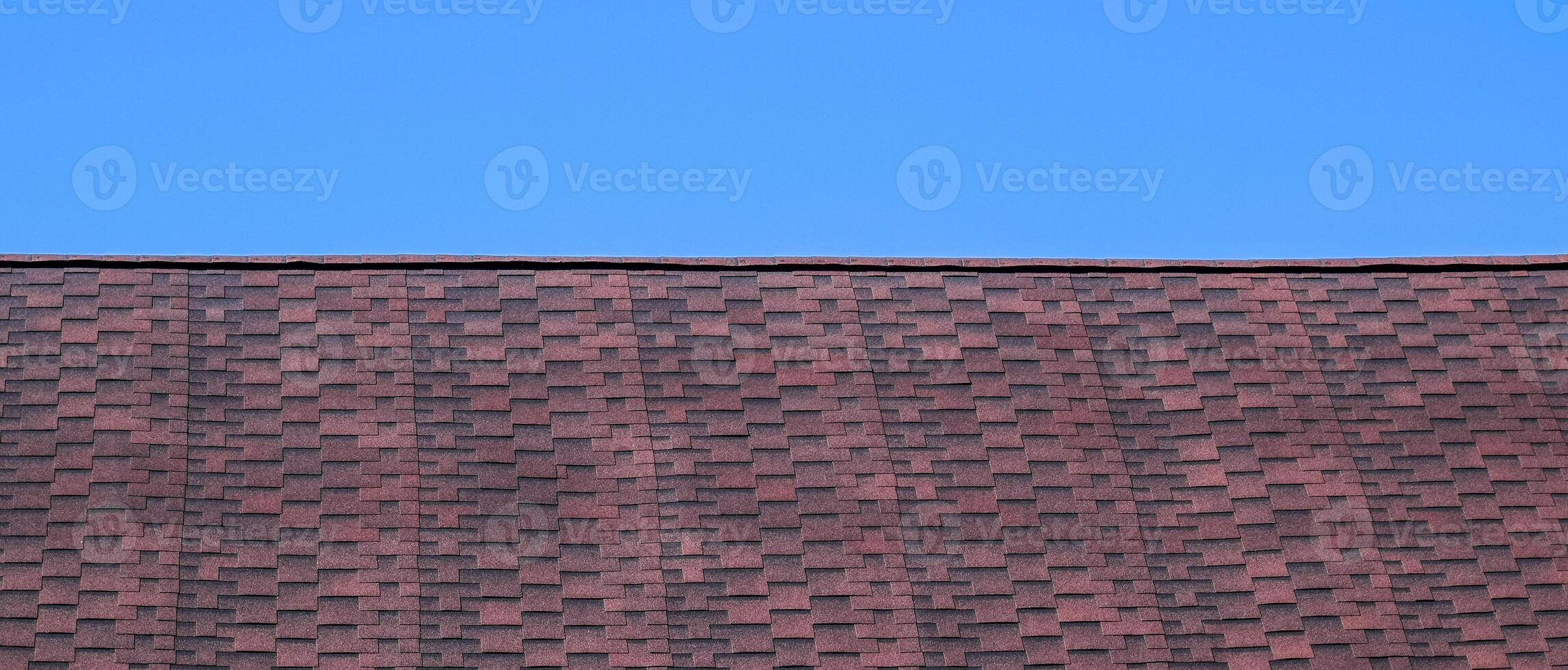 Roof from multi-colored bituminous shingles. Patterned bitumen shingles. Bituminous burgundy roof. photo