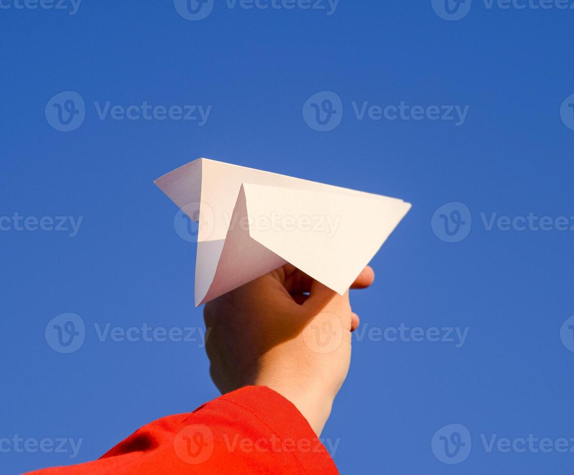 White paper airplane in hand against the sky. A symbol of freedom on the Internet photo