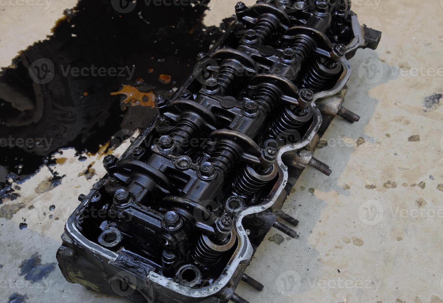 The head of the block of cylinders. The head of the block of cylinders removed from the engine for repair. Parts in engine oil. Car engine repair in the service photo