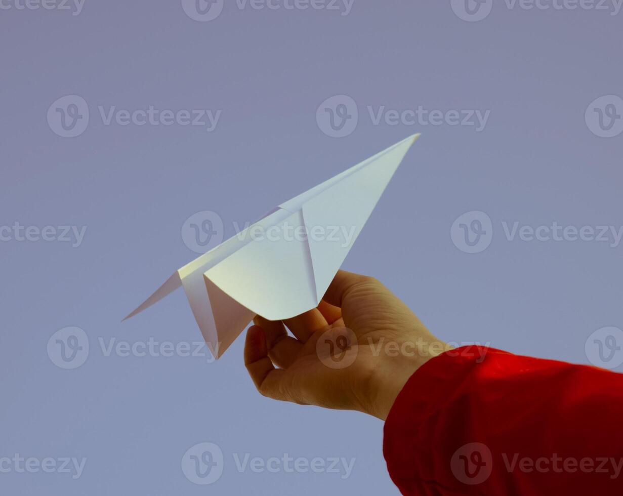 White paper airplane in hand against the sky. A symbol of freedom on the Internet photo