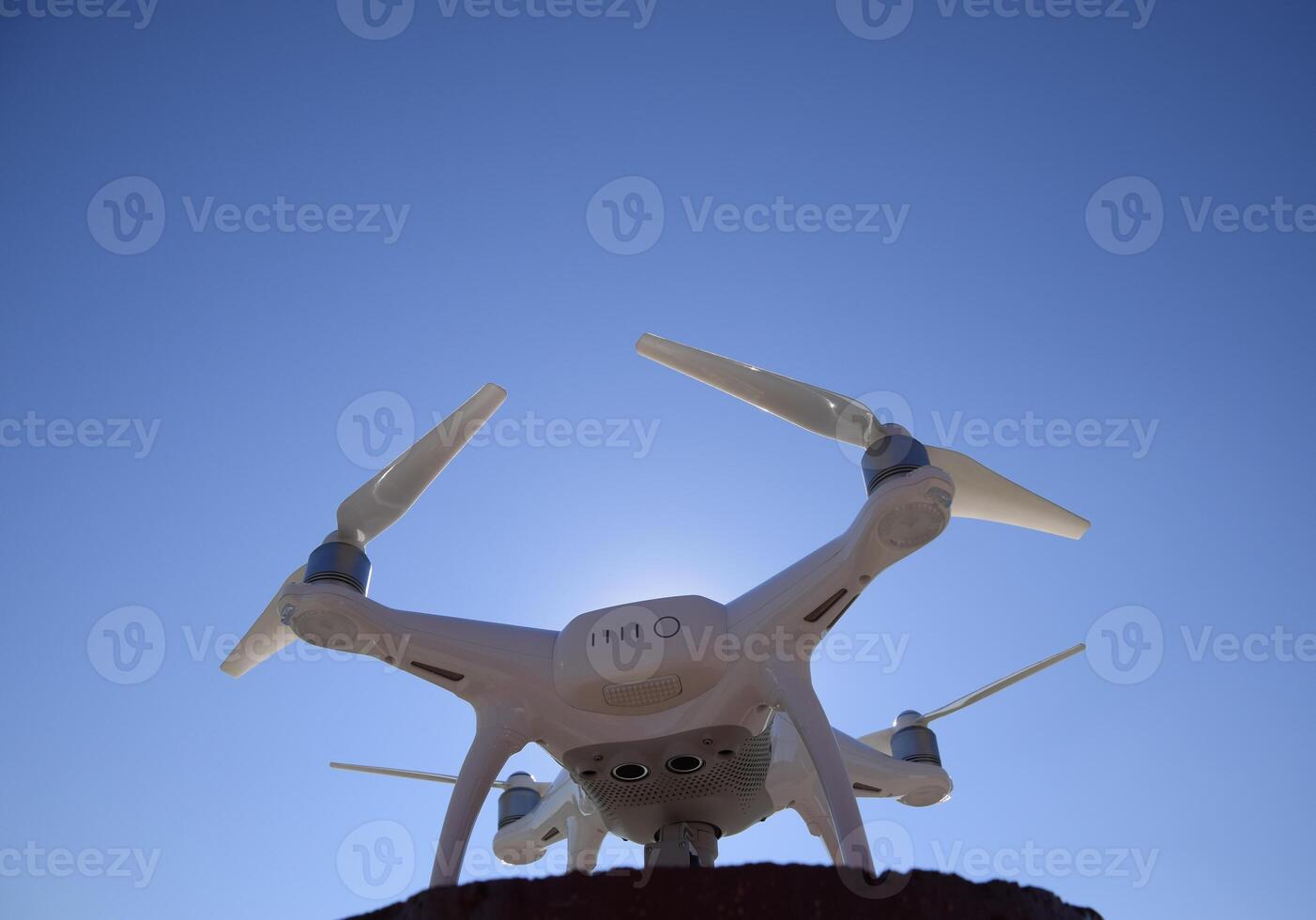 Quadrocopter Phantom 4 against the blue sky in the sun. Backlight. Dron is an innovative flying robot. photo