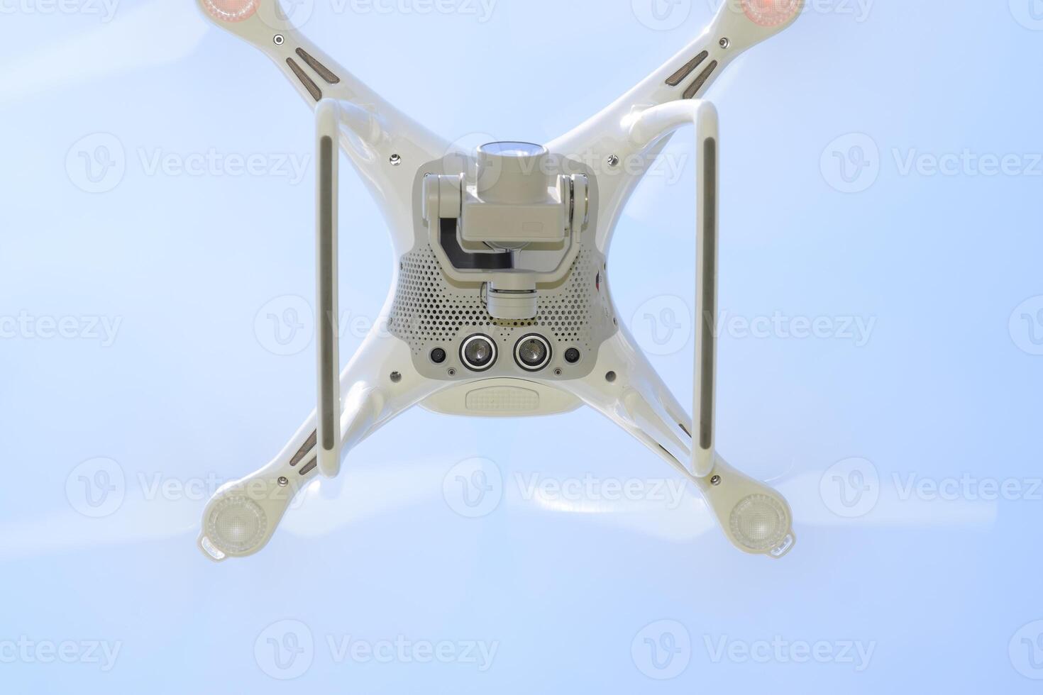 Drone DJI Phantom 4 in flight. Quadrocopter against the blue sky with white clouds. The flight of the copter in the sky. photo