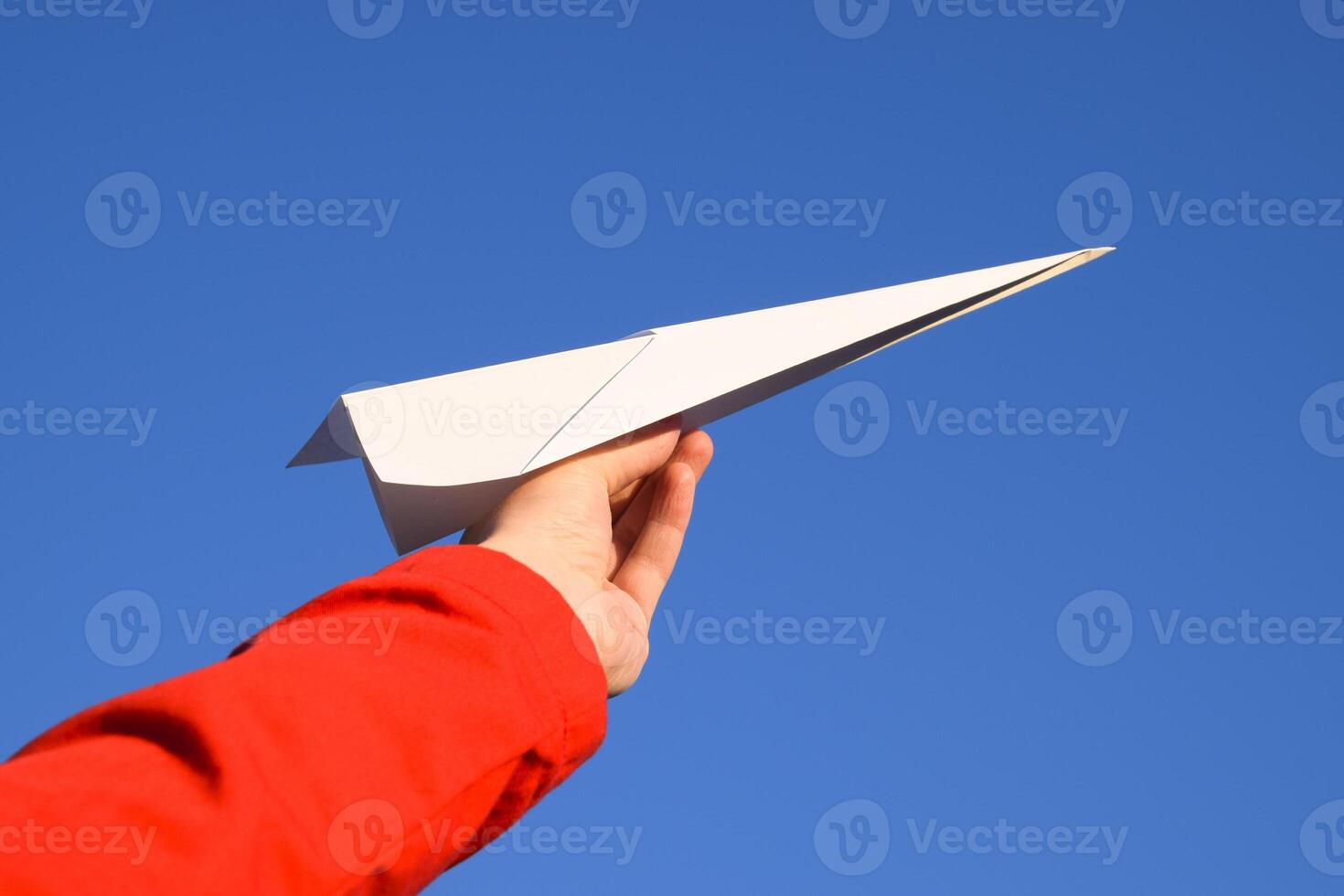 White paper airplane in hand against the sky. A symbol of freedom on the Internet photo