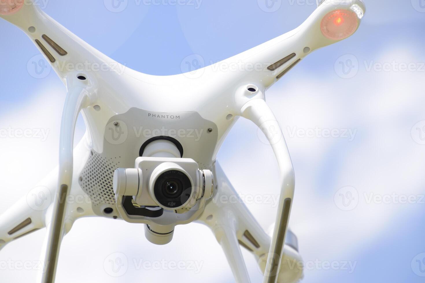 Drone DJI Phantom 4 in flight. Quadrocopter against the blue sky with white clouds. The flight of the copter in the sky. photo