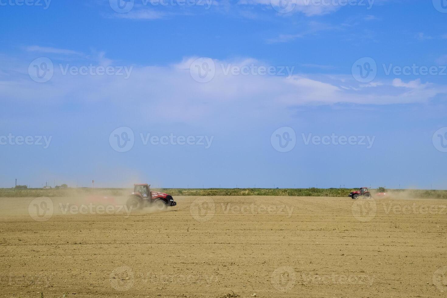 tractor con un calificador alinea el suelo en el campo. el tractor elevado polvo. foto