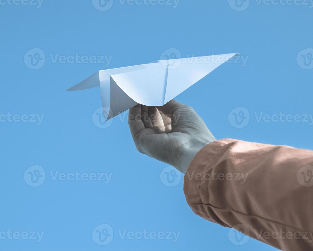 White paper airplane in hand against the sky. A symbol of freedom on the Internet photo