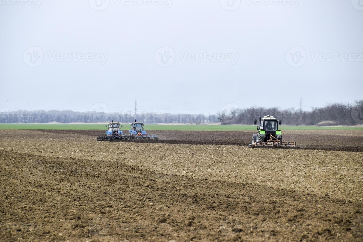 Lush and loosen the soil on the field before sowing. The tractor plows a field with a plow photo
