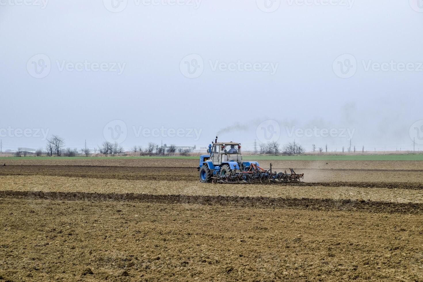 Lush and loosen the soil on the field before sowing. The tractor plows a field with a plow photo