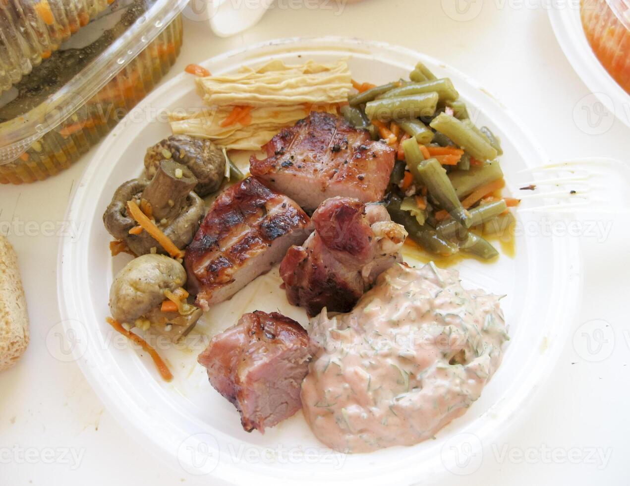 Shish kebab in disposable dishes. Fried meat in plastic plates. photo