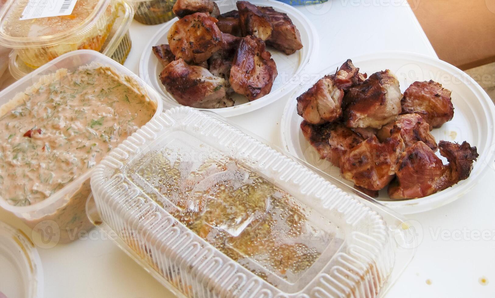 Shish kebab in disposable dishes. Fried meat in plastic plates. photo