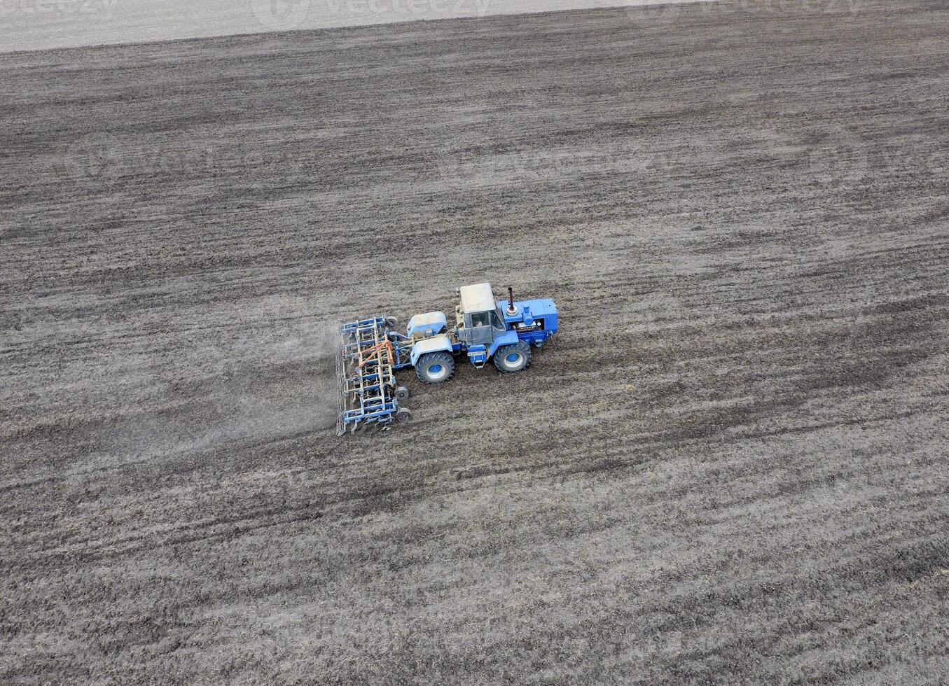 The tractor plows the field. Under sowing, the soil is loosened on the field. photo