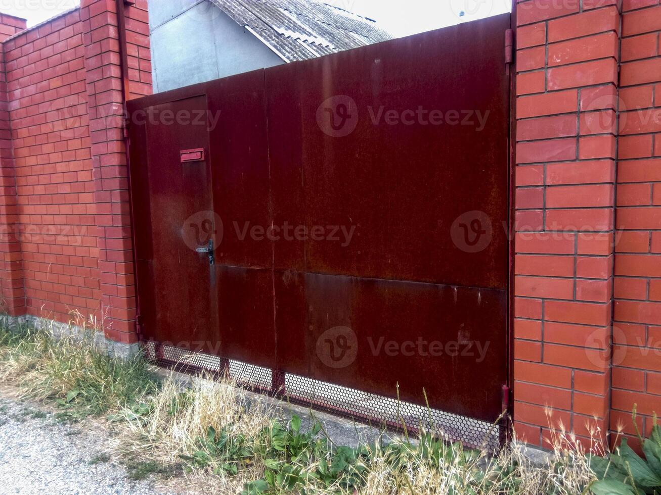 Steel rusty gates and a red brick fence. photo