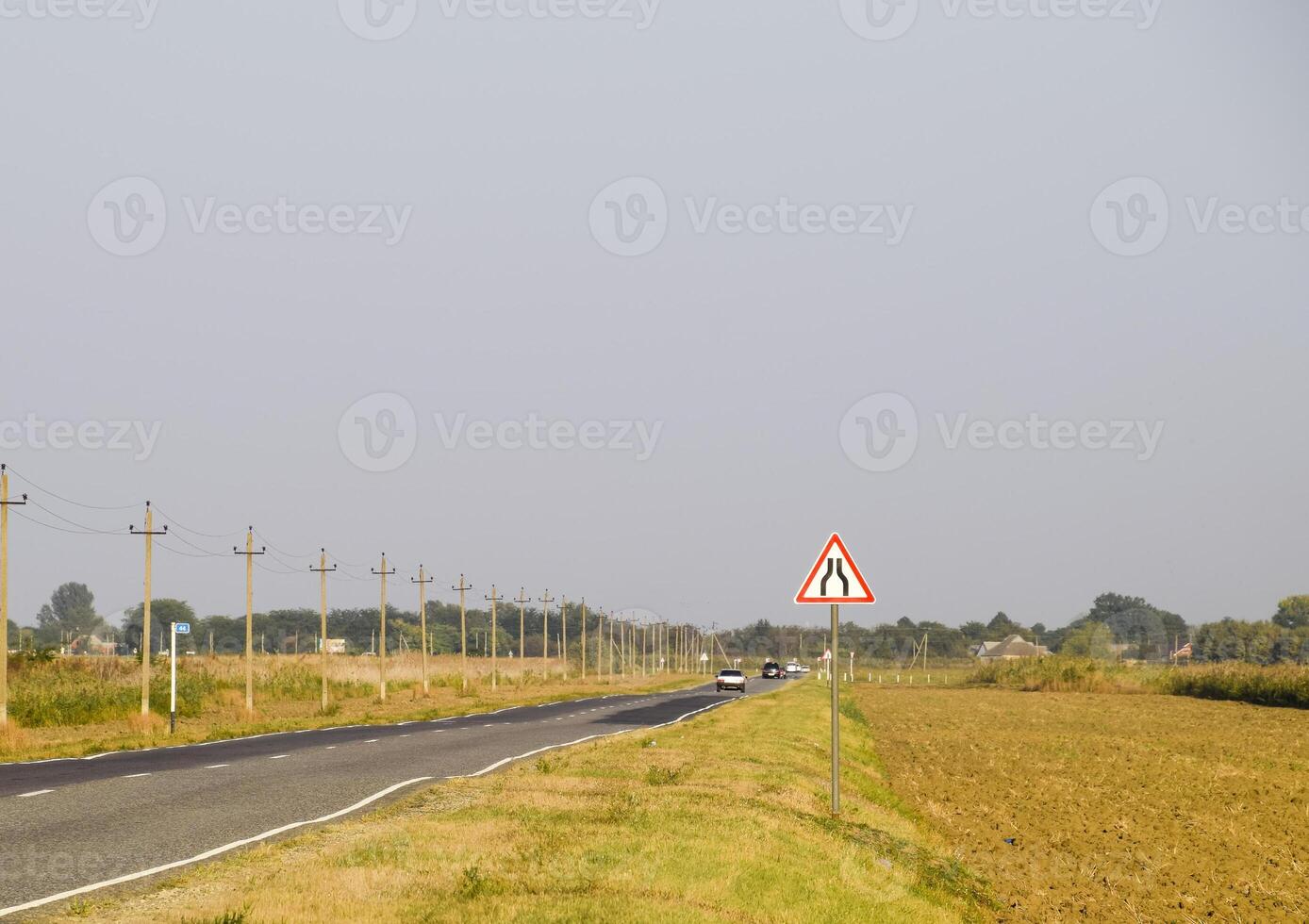 Interurban trail. Sign of narrowing the road. The asphalt road and the grassy side of the road. photo