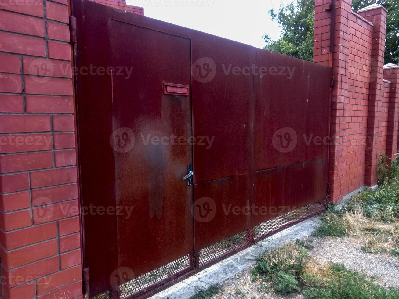 Steel rusty gates and a red brick fence. photo