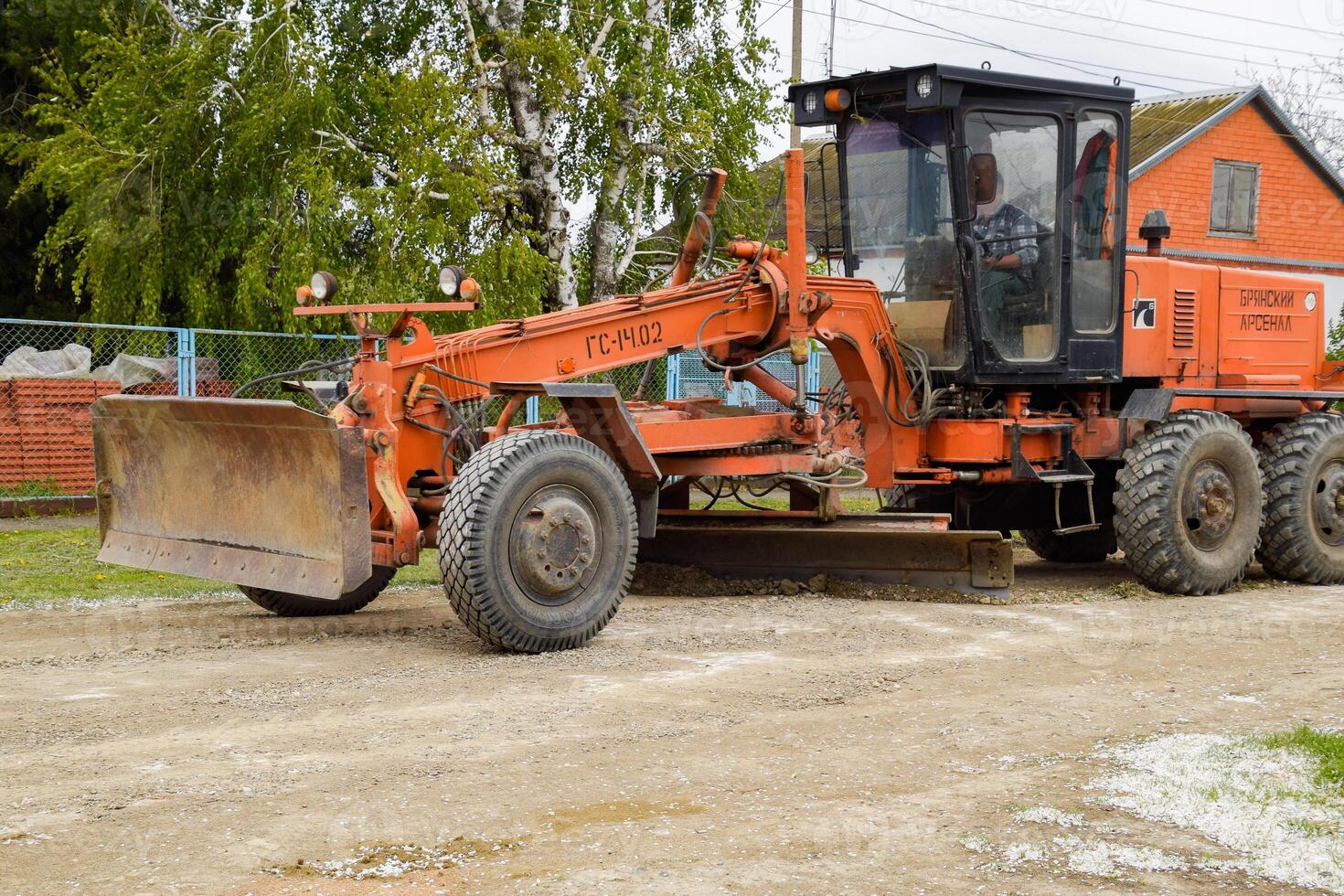 Grader on a dirt gravel road. Street repair by adding rubble. photo