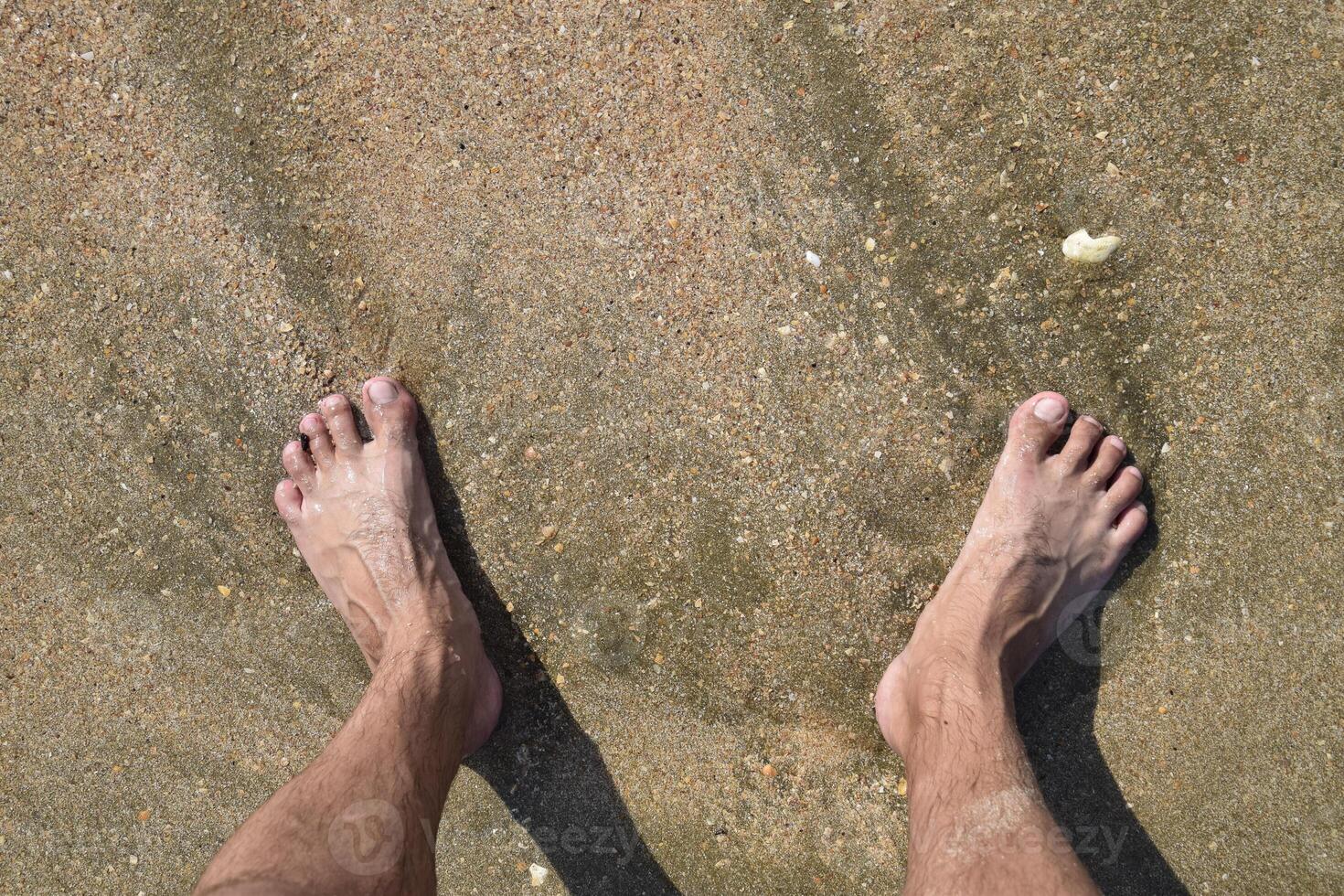Legs men on the sea sand near sea wave photo