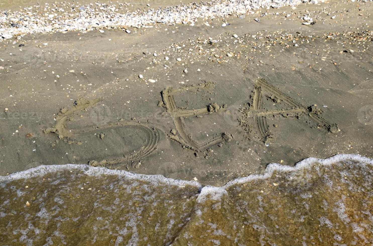 el inscripción de el mar en el arena. costero arena y ondas. inscripciones en el apuntalar foto