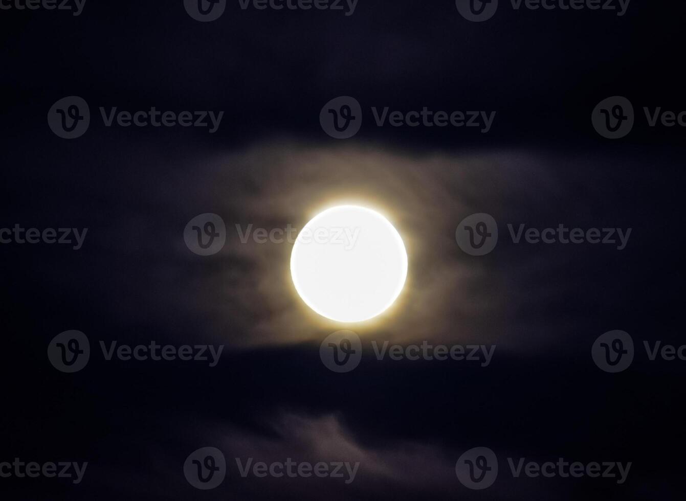Moon in the night sky. Near the moon a small amount of clouds photo