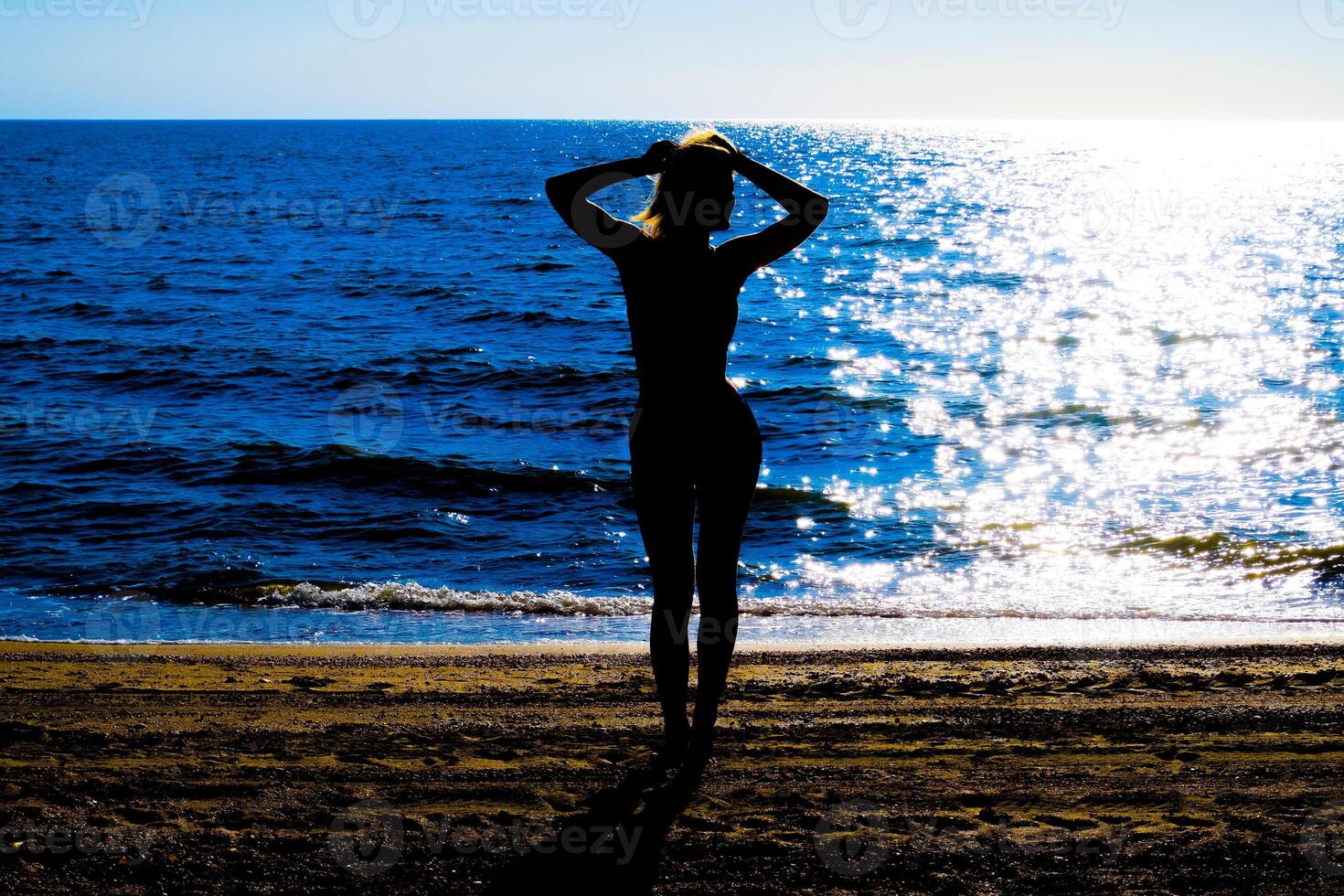 silueta de un hermosa niña figura en el antecedentes de el mar a puesta de sol foto