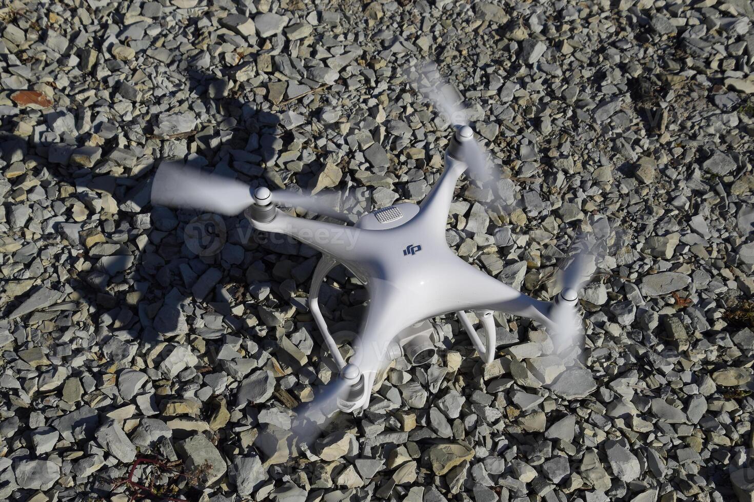 Drone Phantom 4 stands on the gravel and turns the propellers. Preparation for flight of the drone. photo