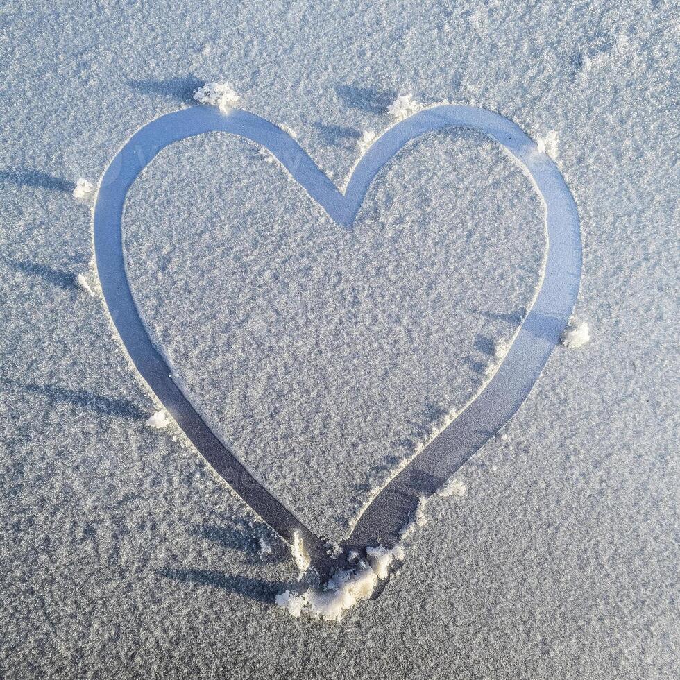 corazón dibujado en el escarcha en el capucha de el coche foto