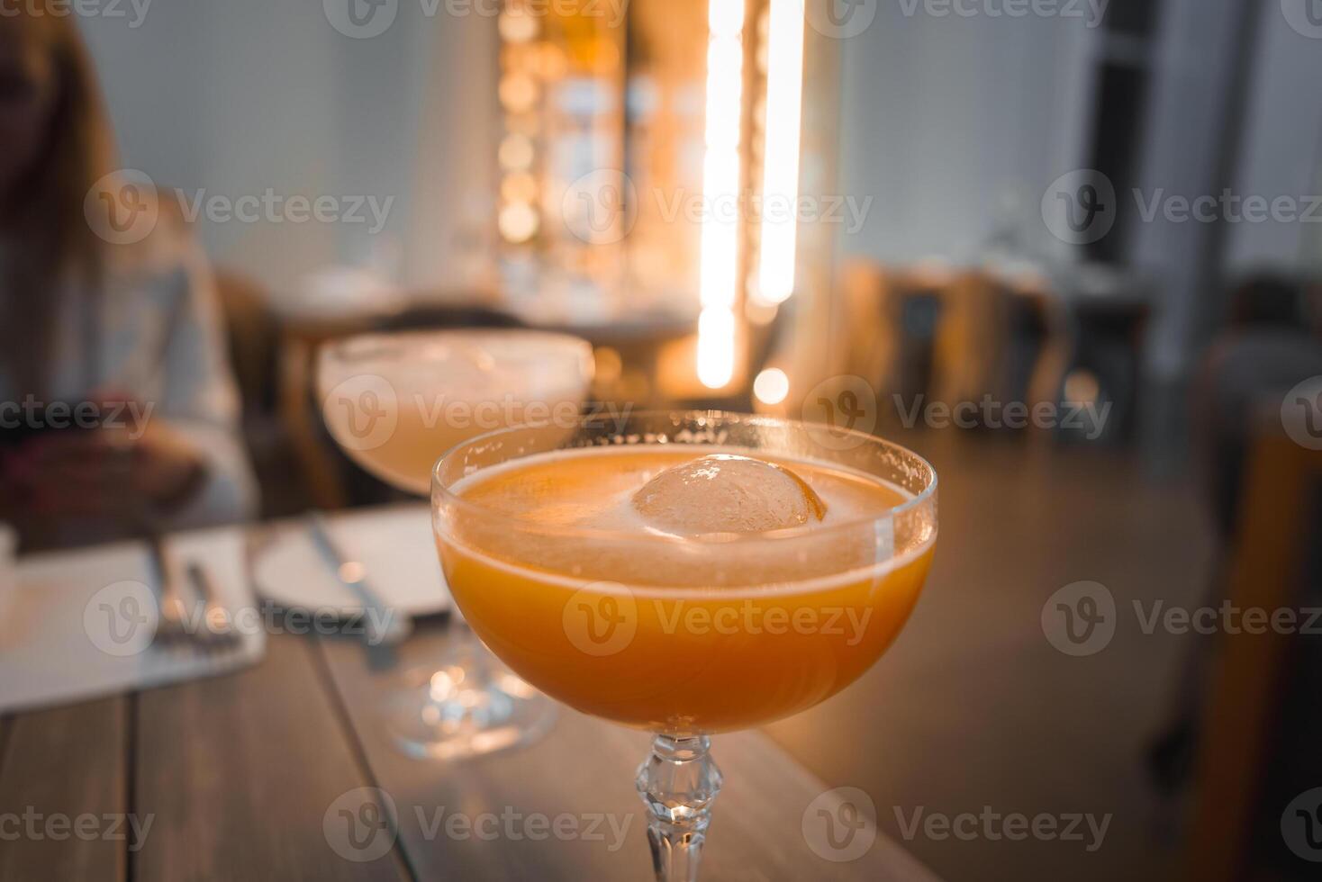 Chilled Orange Cocktail in Elegant Glass with Cozy Dining Ambiance photo