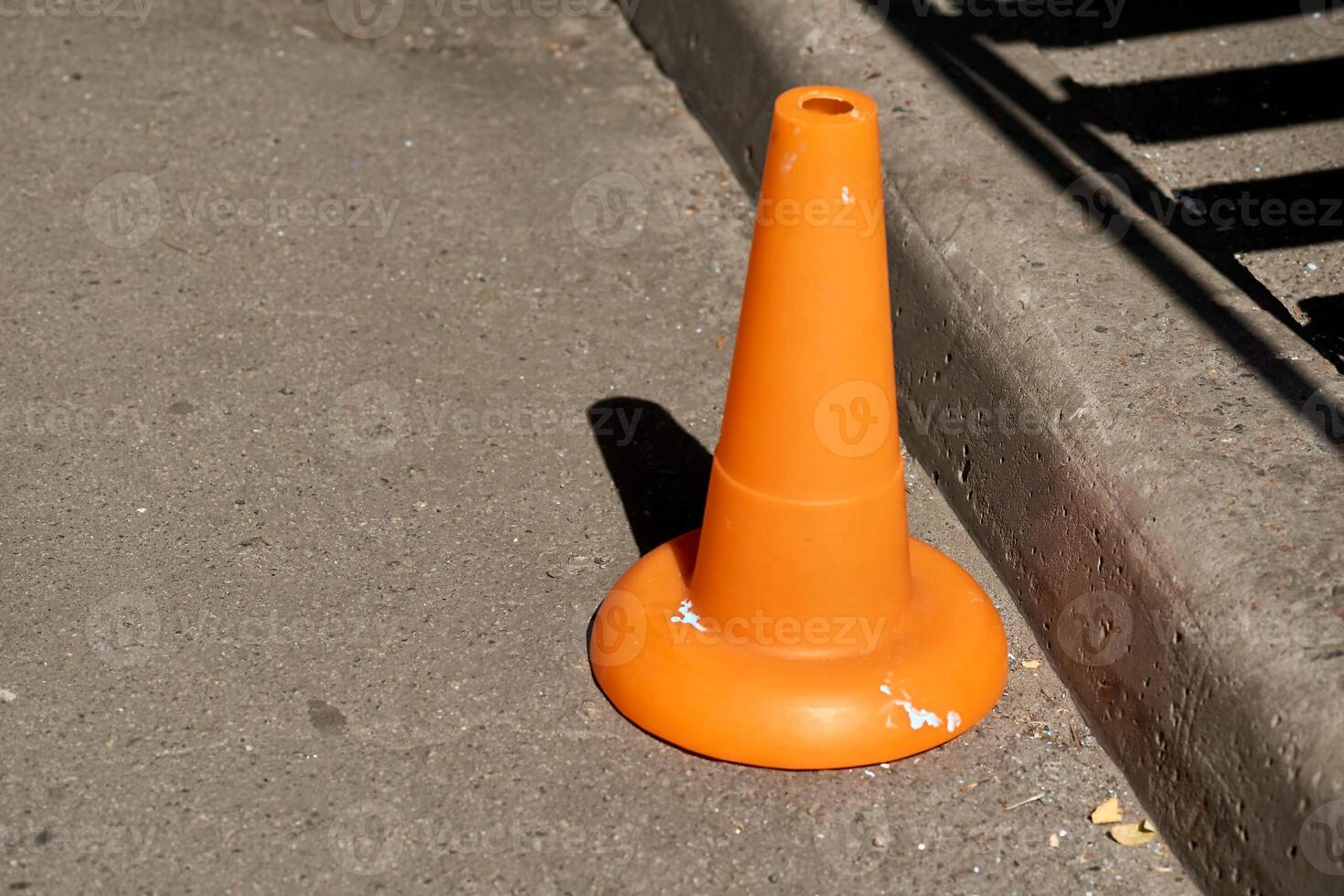 A traffic orange cone is used as a barrier during road construction work photo