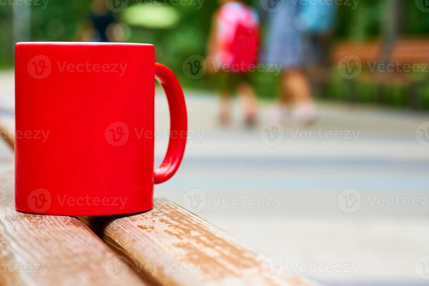 Red ceramic cup on a wooden bench in the park photo