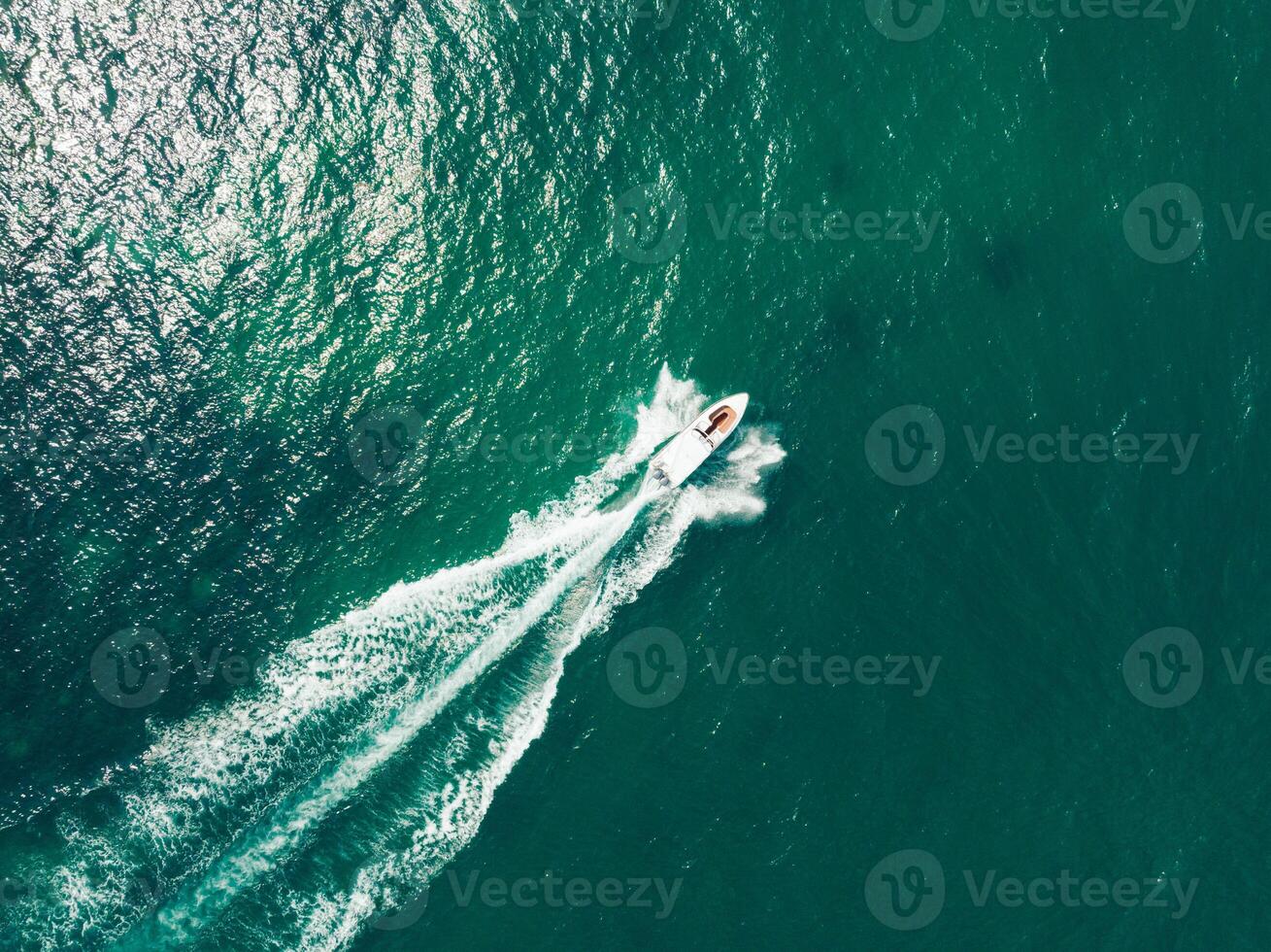 a boat traveling through the ocean with a wake photo