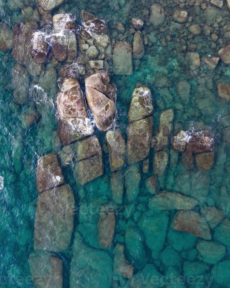 an aerial view of rocks and water in the ocean photo