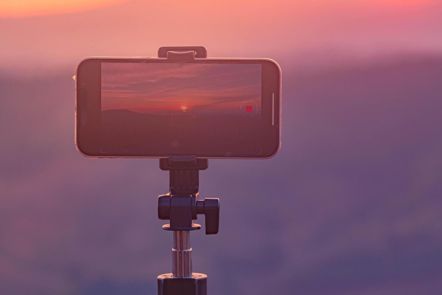A smartphone is recording the sun setting over a mountain range. photo