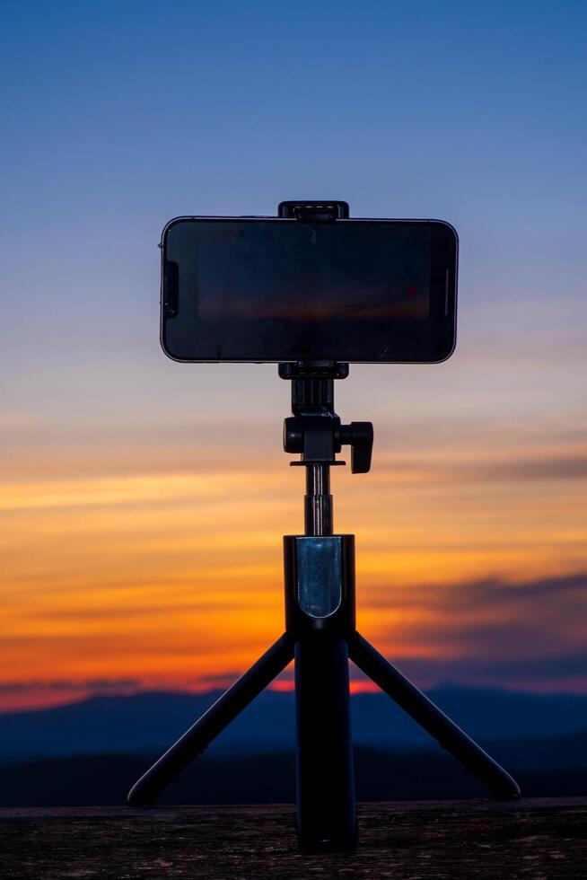 A smartphone is recording the sun setting over a mountain range. photo