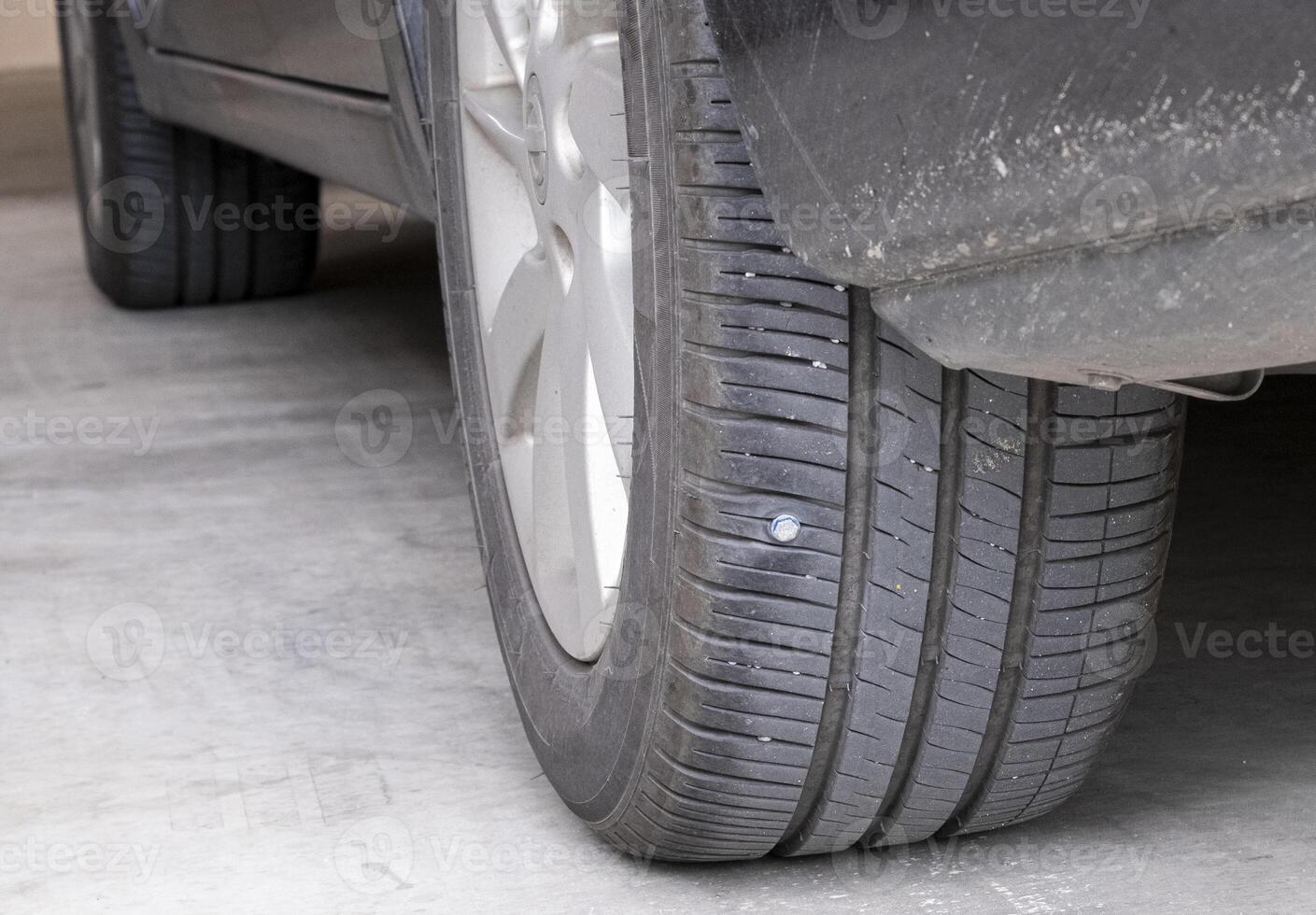 metal screws put on car tires low pressure. Closeup of car tire punctured with iron screws Tire puncture on black background with copy space. selective focus photo