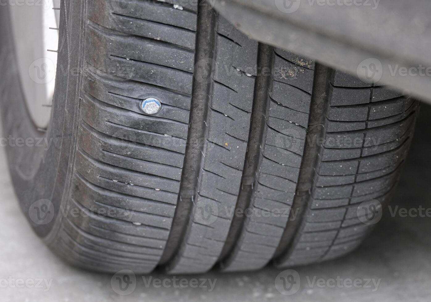 metal screws on car tires low pressure. Closeup of car tire punctured with iron screws Tire puncture on black background with copy space. selective focus photo