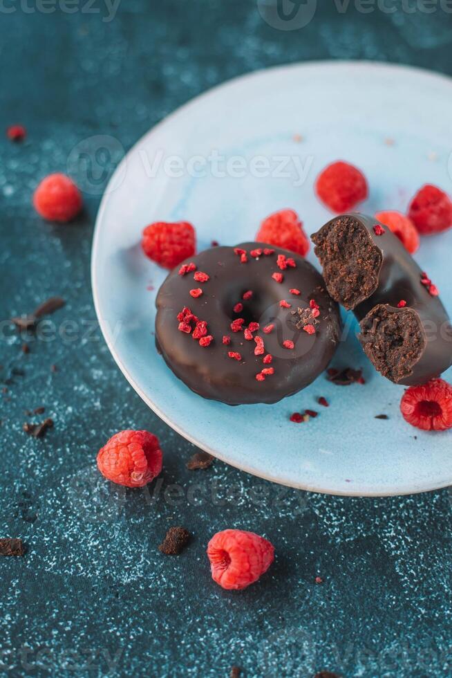 Chocolate donuts with fresh raspberries on a blue plate photo