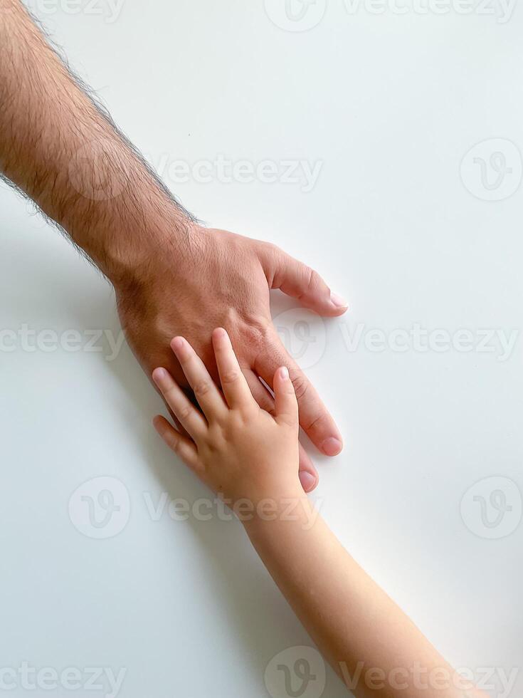 Adult and child hold their hands together. Fathers Day Child gives hand to adult photo