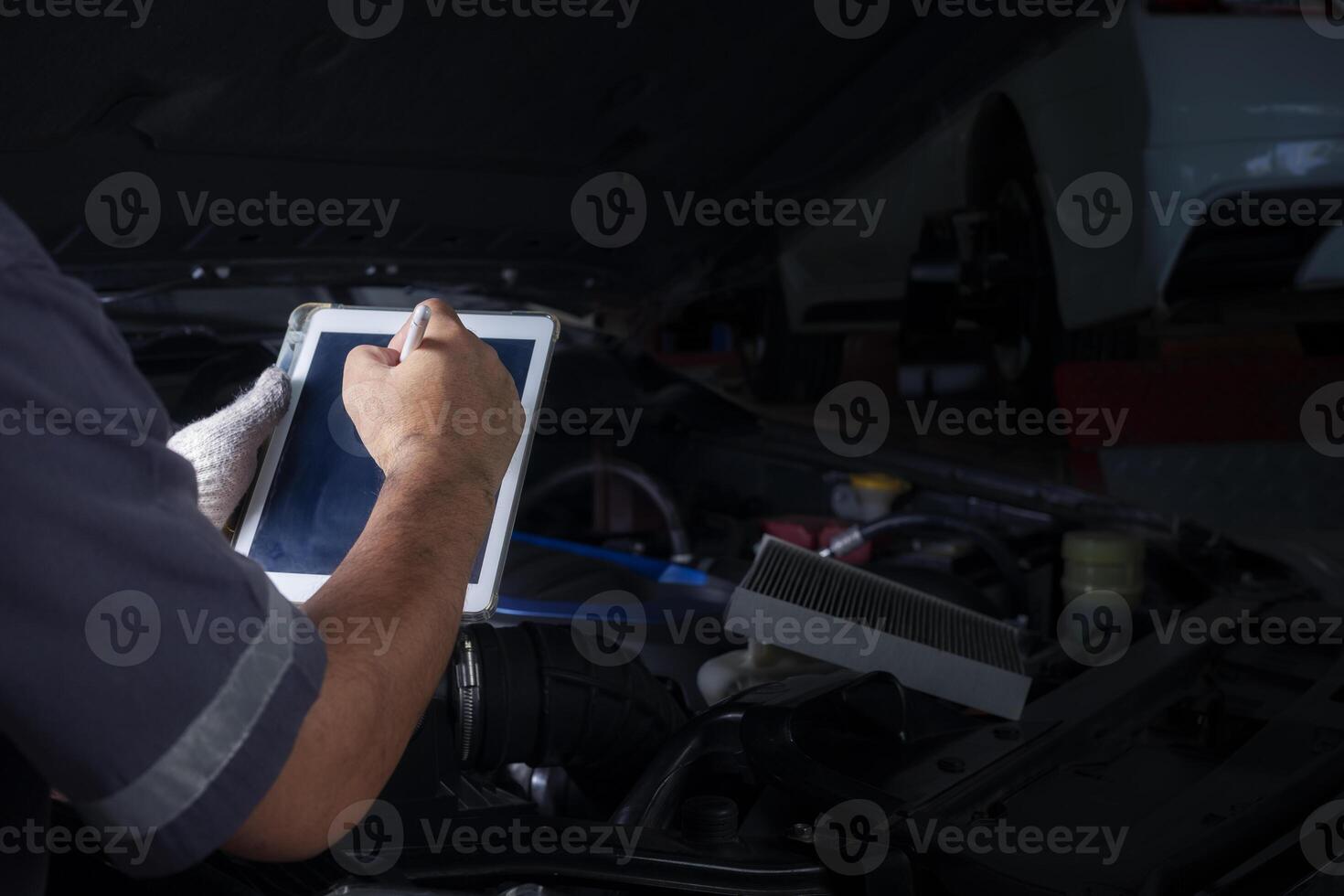 The mechanic checks the engine using tablet computer technology. Complete with wrench tool Auto mechanic working in the garage. Repair service. photo