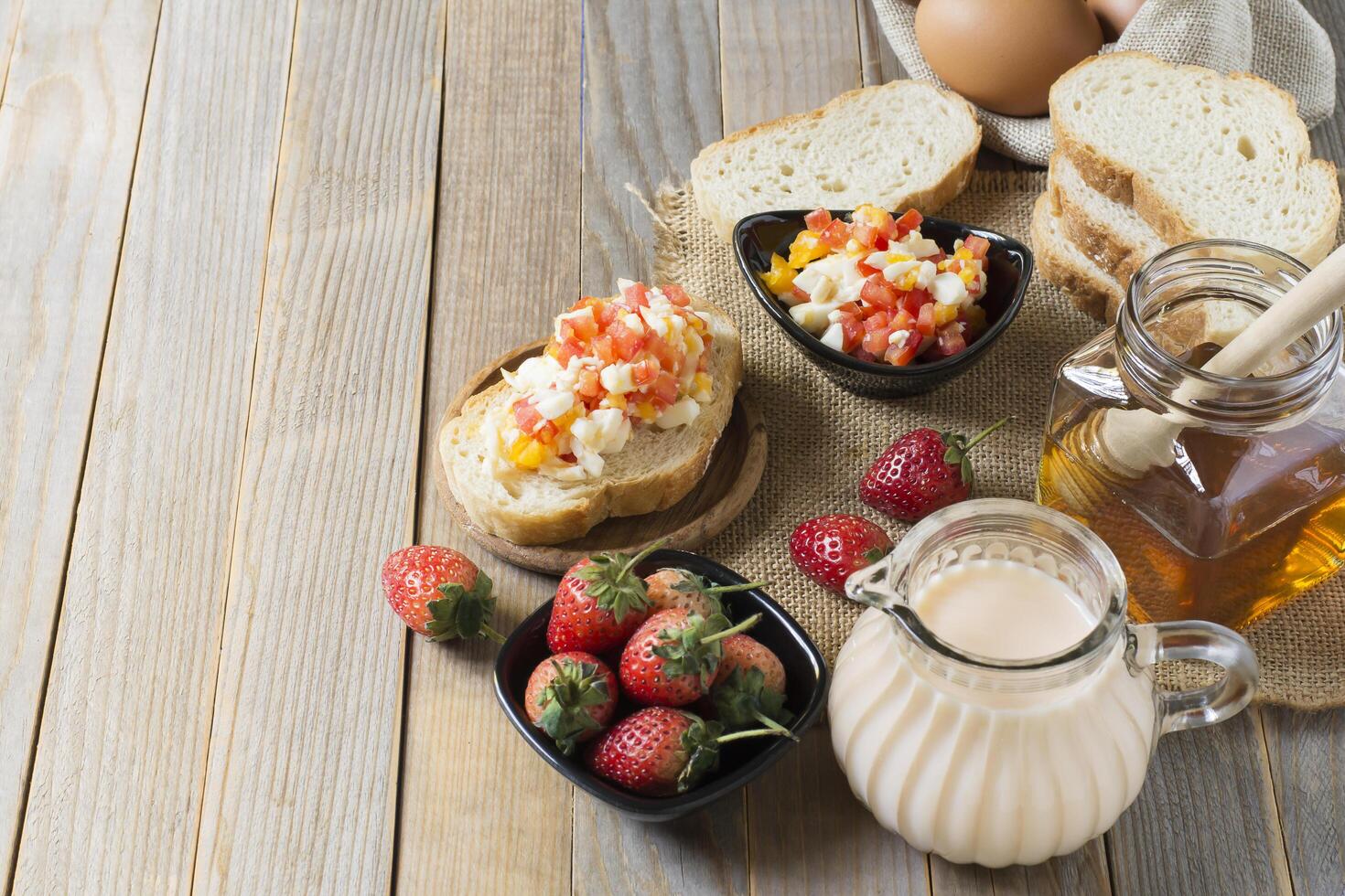Breakfast bread with strawberry milk And eggs laid on the old wooden floor with copy space photo