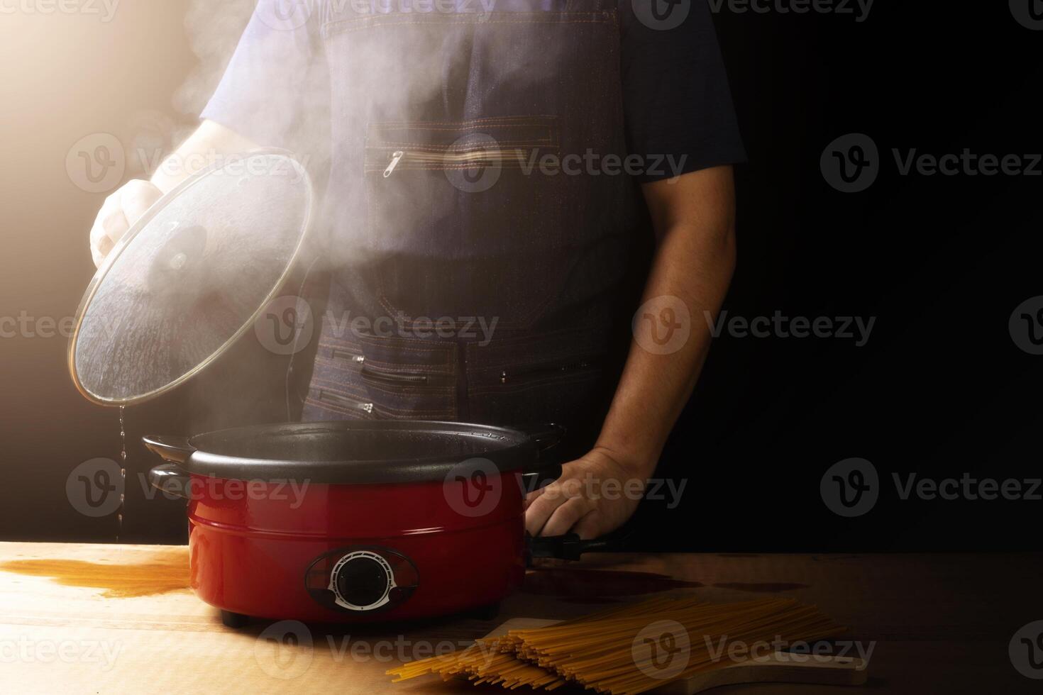 el cocinero hace espaguetis en un maceta en el cocina, el atmósfera es rústico. molecular gastronomía gratis espacio para publicidad, negro, oscuro antecedentes. foto