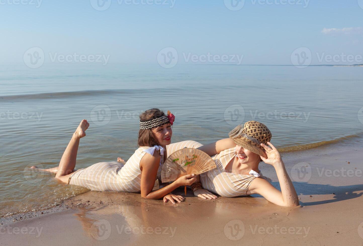 Two young women in retro swimsuits by the sea photo