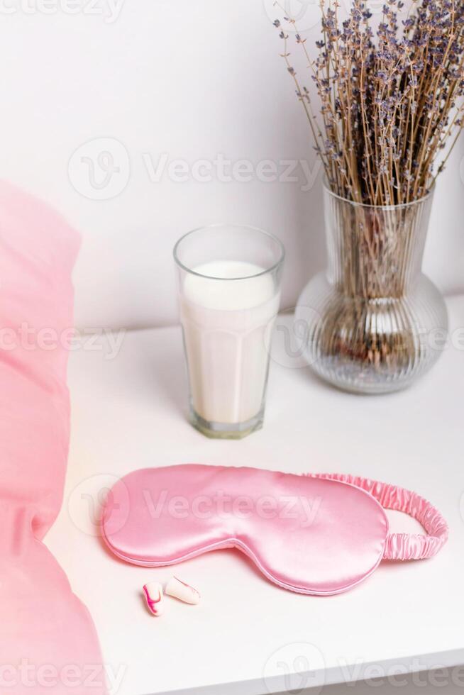 Bedside table with a silk sleep mask, earplugs and lavender and warm milk for a good night's sleep. All conditions for good deep sleep. Help for falling asleep photo